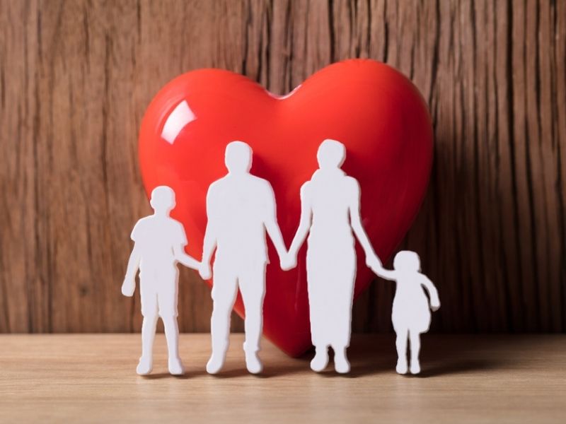 Close-up Of A Family Holding Hands Beside Red Heart